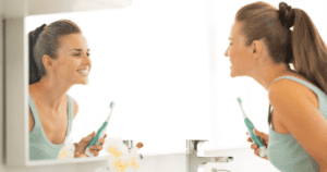 A woman looking in the mirror brushing her teeth