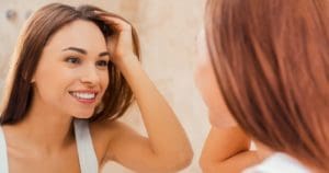 A woman looks at her dental bonding in mirror