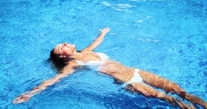 A woman in a white bikini relaxes in a pool